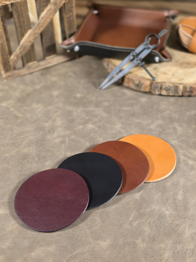 Set of four leather coasters in different colors arranged on a leather surface