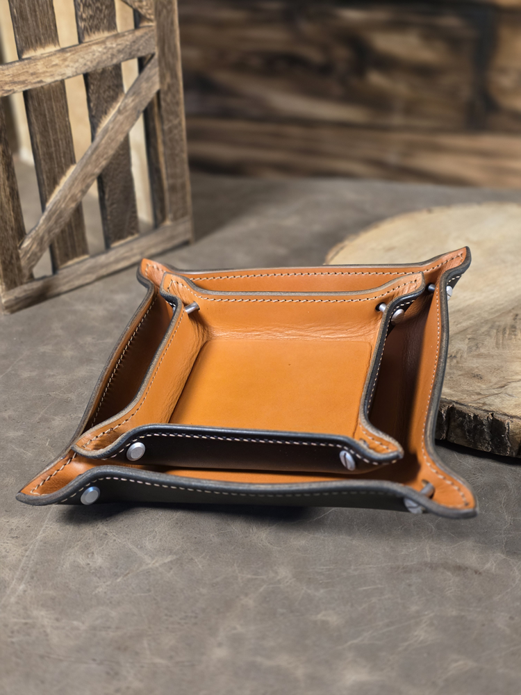 Pair of Hellhound valet trays nested inside each other, with tan and black leather and contrast stitching, sitting on a table