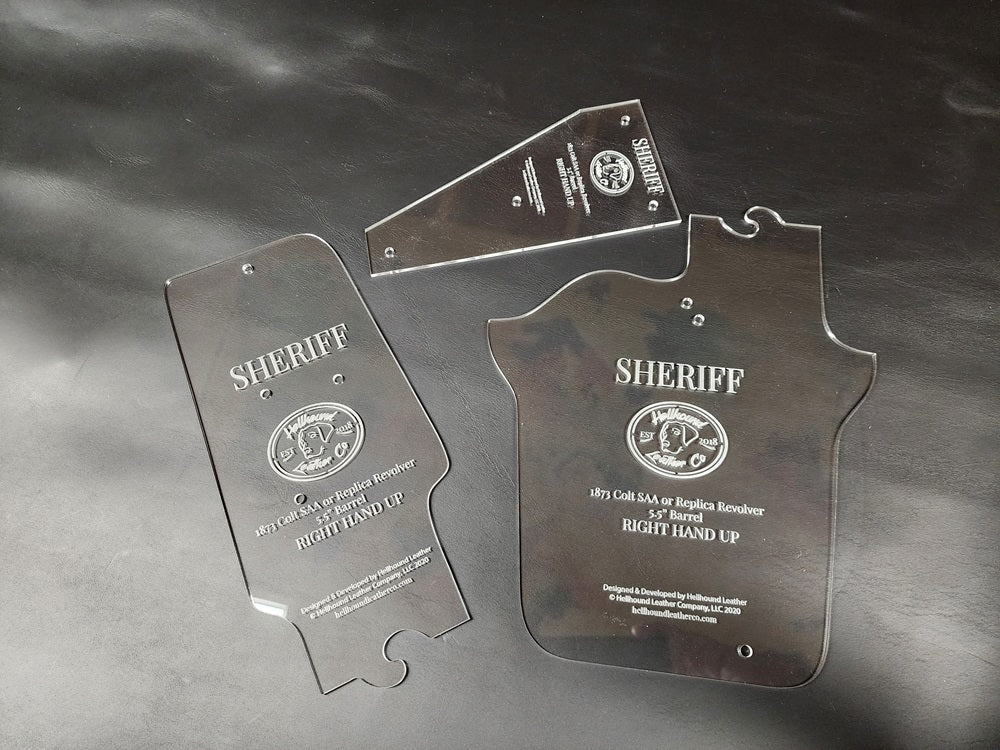 The three acrylic pieces to the sherrif western pattern laying on a black leather background.