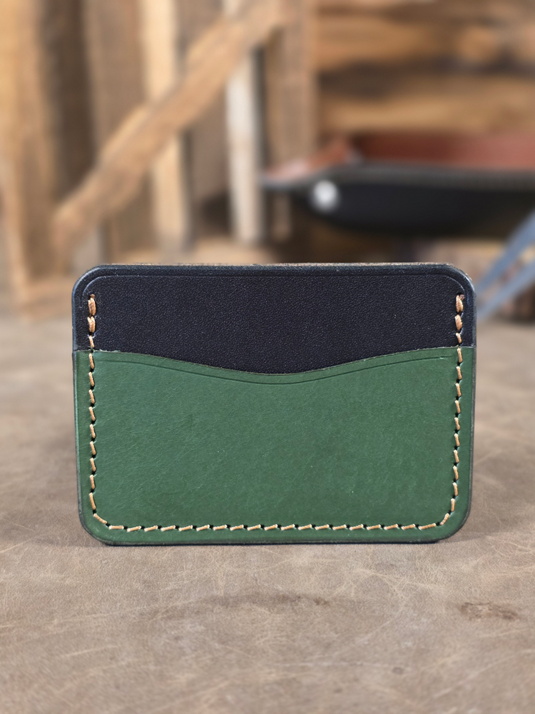 Green and black leather wallet on a concrete surface with blurred background
