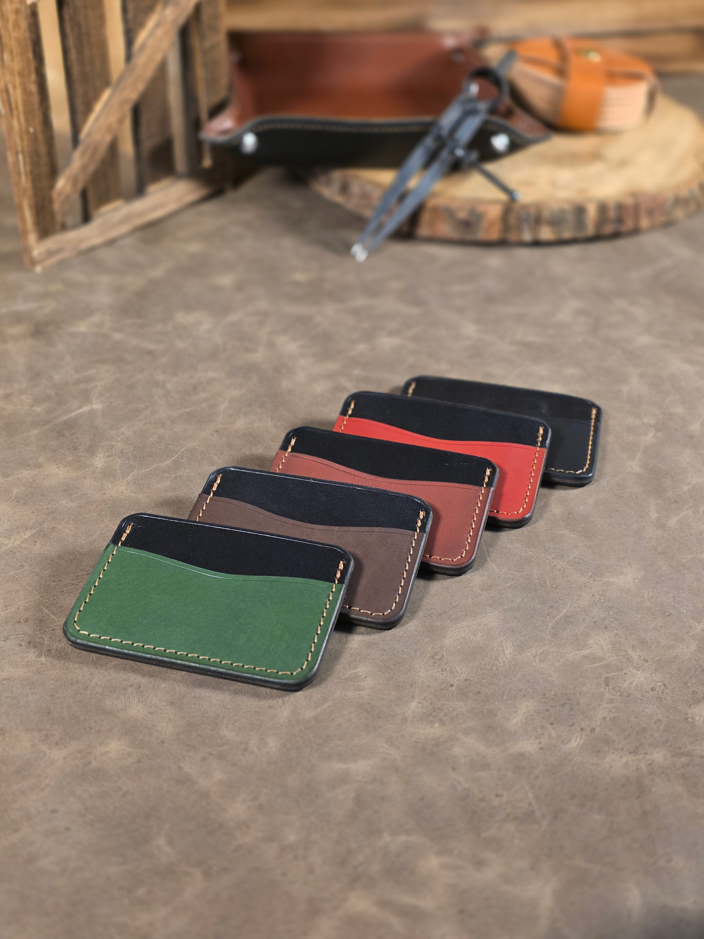 Set of leather card holders in various colors on a textured surface.