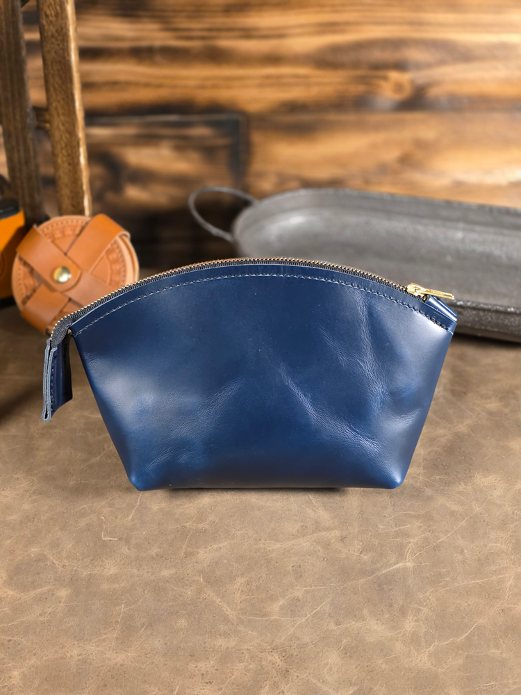 Blue leather pouch on a textured surface with a wooden background