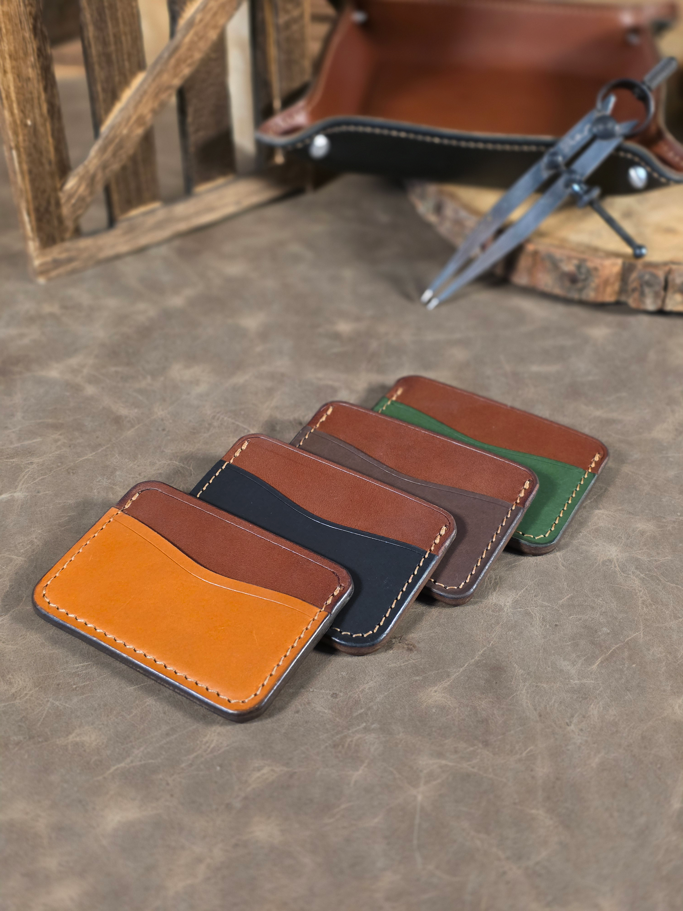 Set of leather card holders in various colors on a textured surface.