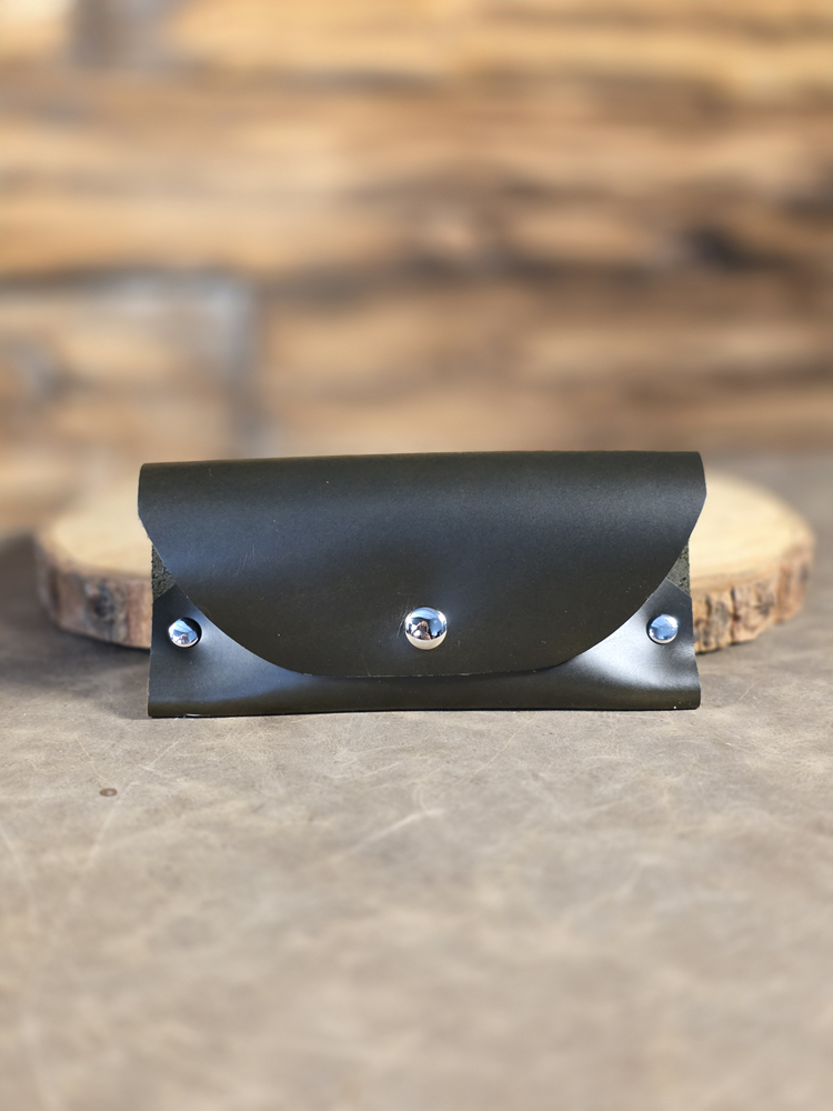 Green leather wallet with metal studs on a wooden surface