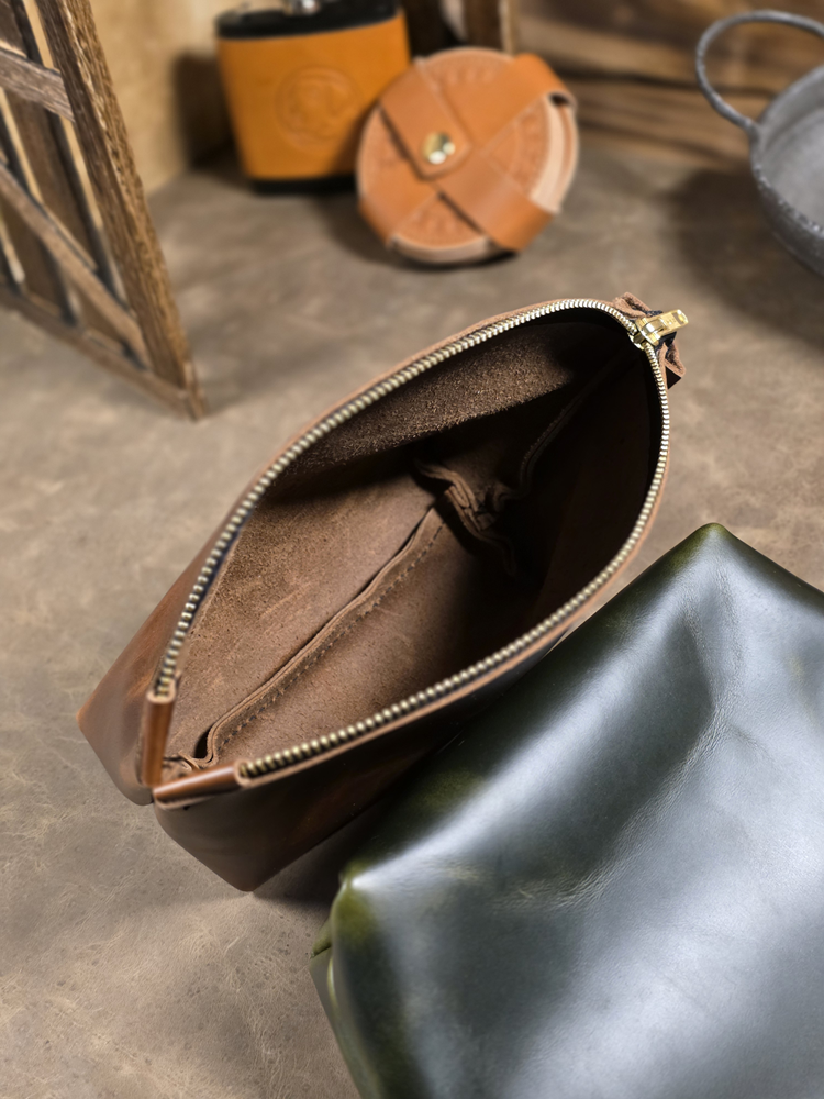 Interior view of Balmoral Cosmetics Pouch, unlined full grain leather on a leather surface and blurred background.