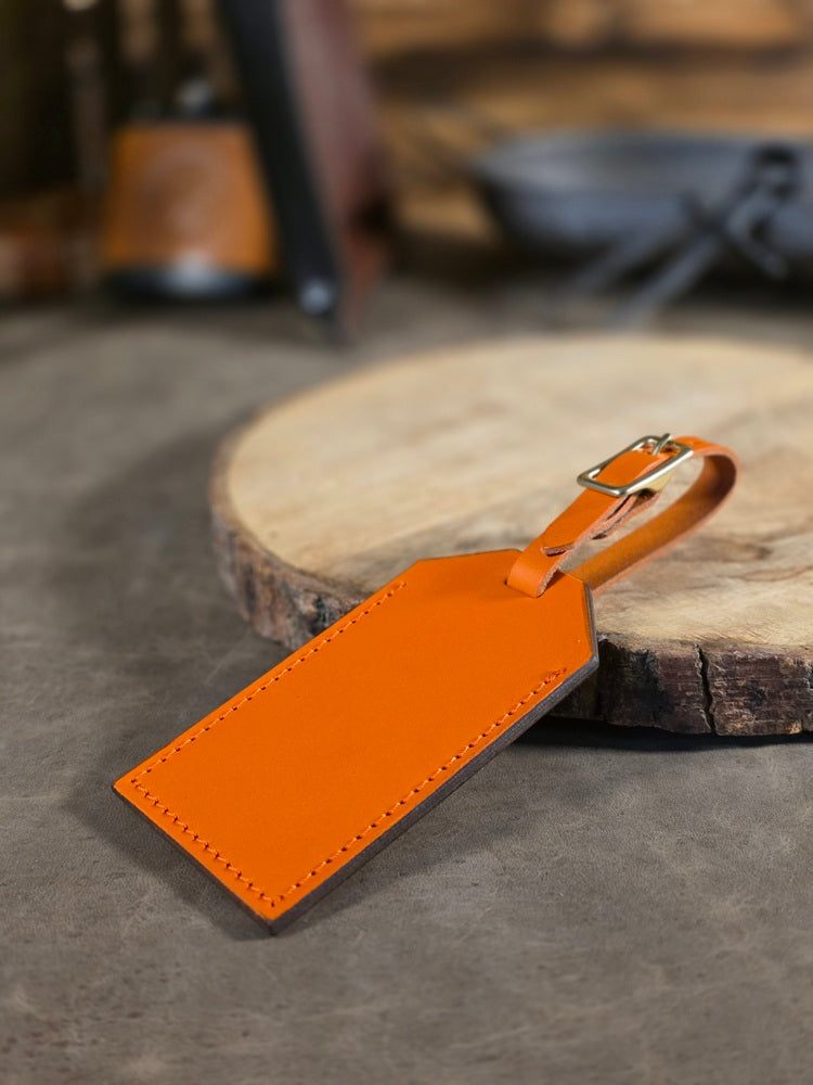 Orange leather luggage tag on a wooden surface with blurred background