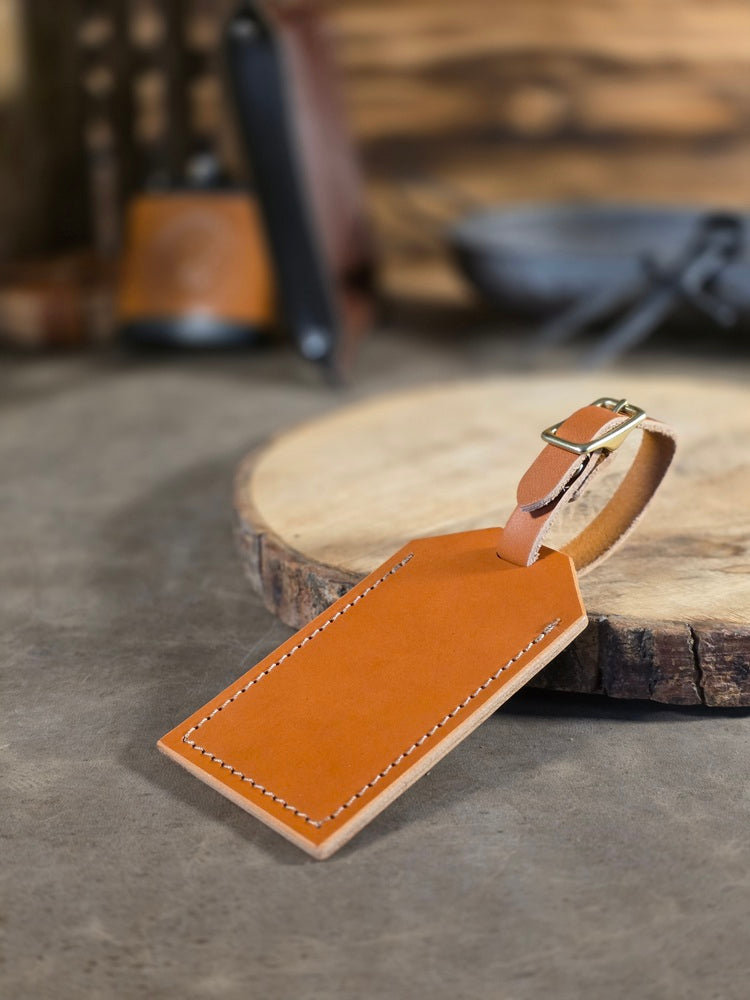 Brown leather luggage tag on a wooden surface with a blurred background