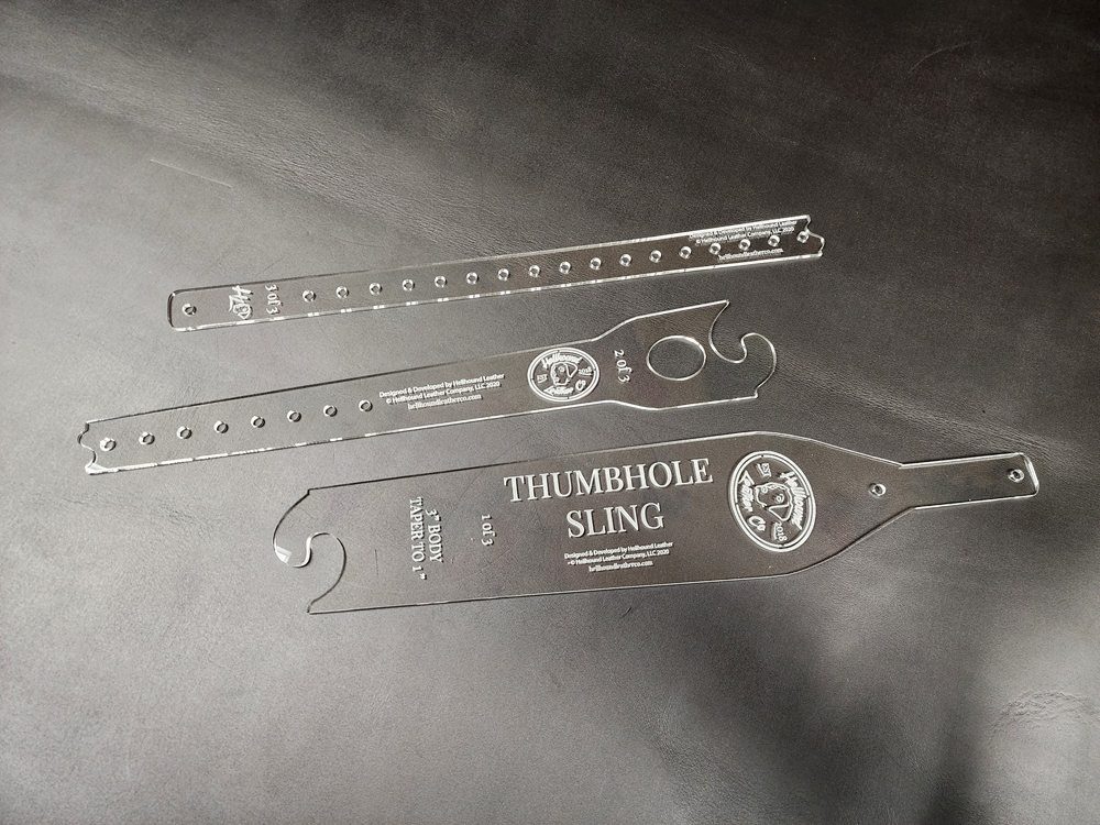 Three clear acrylic pieces of a sling template sitting on a black leather background