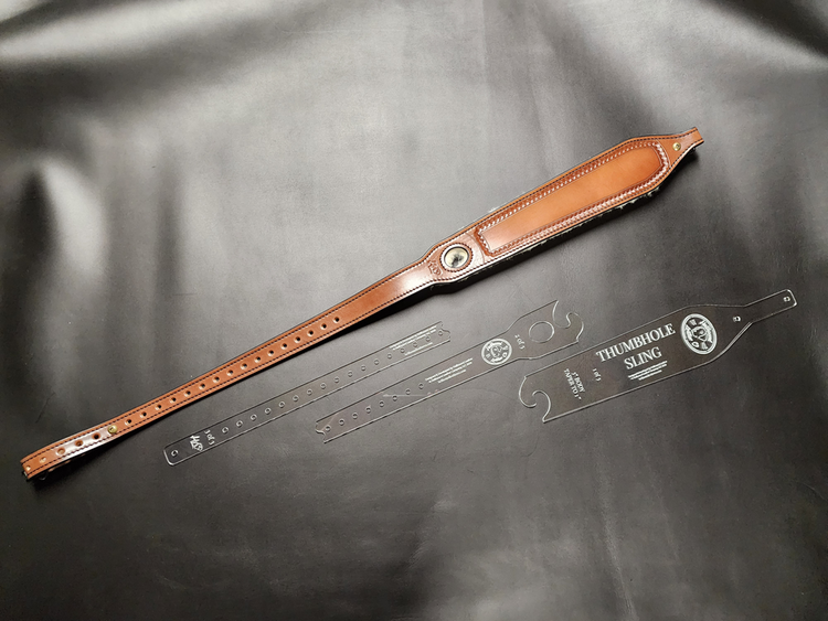 Brown leather vintage thumbhole sling next to a jigsaw pieces of the acrylic pattern.