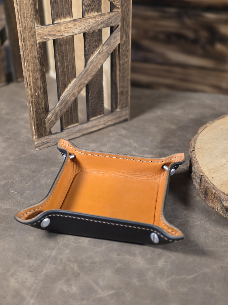 Small two-tone tan and black ring tray on textured rustic table