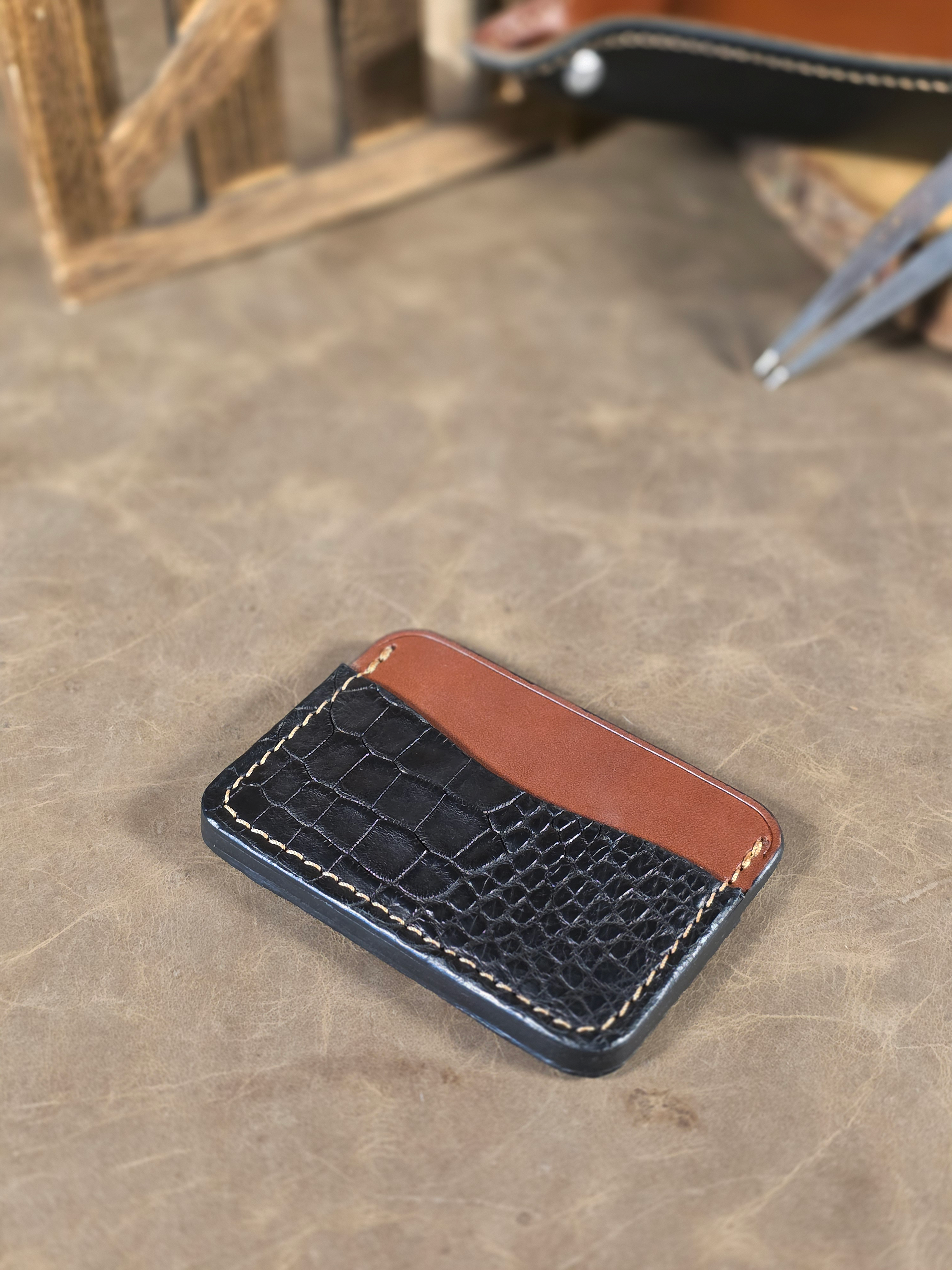 Black alligator with brown leather cardholder on a textured surface