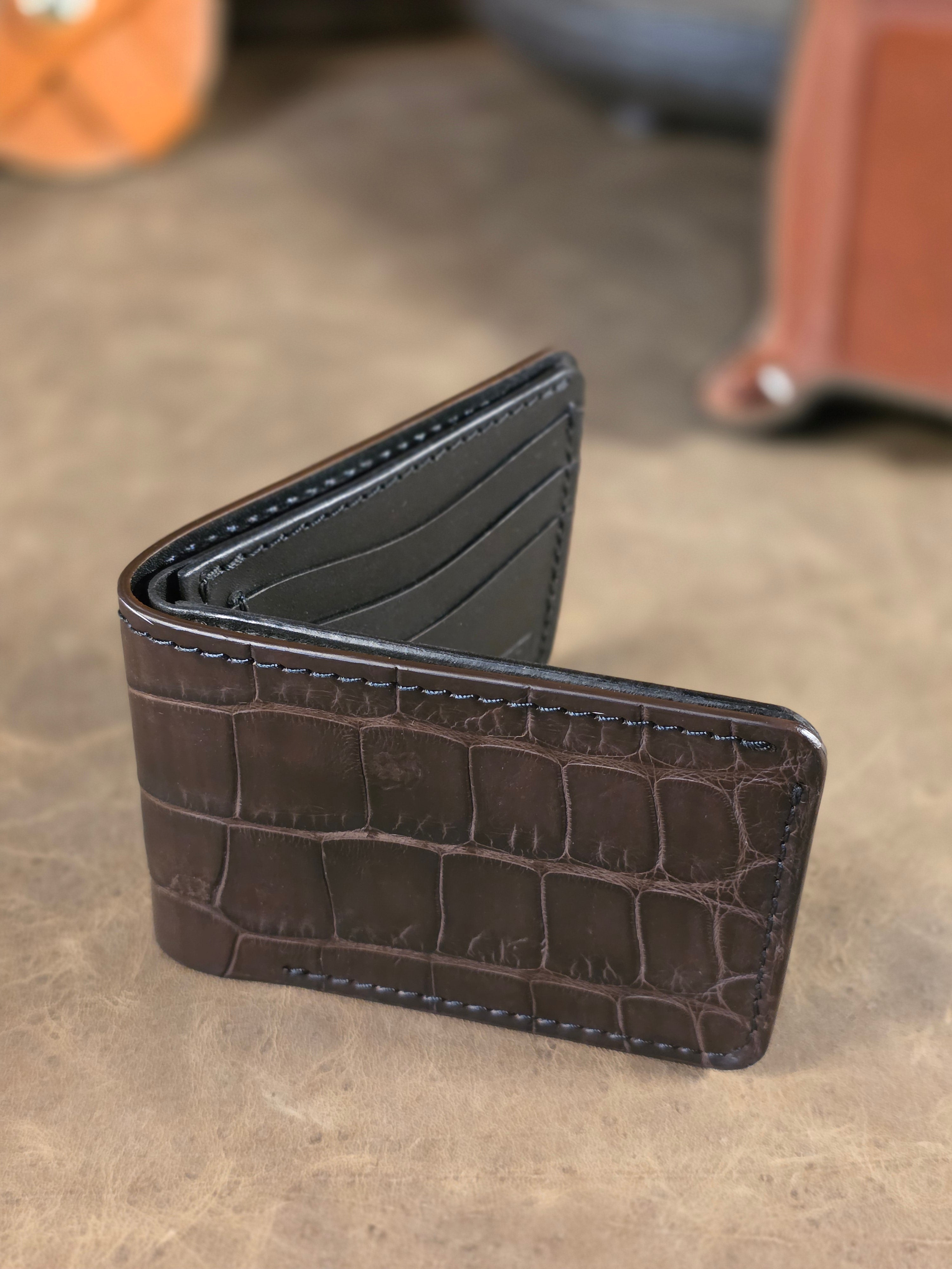 Closeup view of the top edge of the Sobek deep brown alligator wallet. The exterior edge is brown, while the black interior leather has a black edge to match.