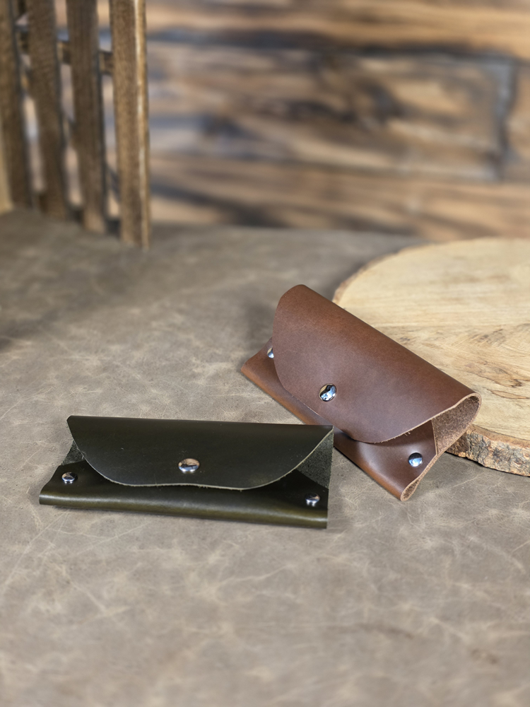 Two sunglass cases crafted in soft leather with silver buttons resting on a table