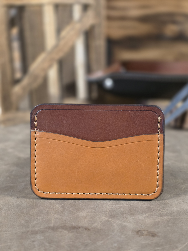 Two-tone brown and tan leather card wallet with a blurred background