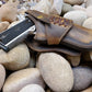 Rustic leather holster for 1911 sitting on river rocks