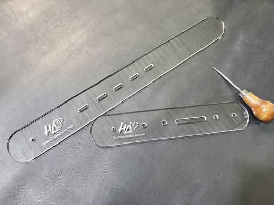A buckle and billet end template, commonly used in leathercraft and made from acrylic, sit atop a gray background.