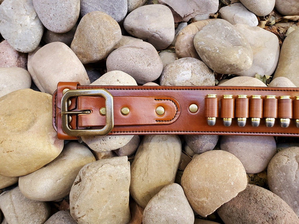 View of the buckle end of the brown leather gunfighter belt, the piece is finished with solid brass hardware and a solid brass buckle.