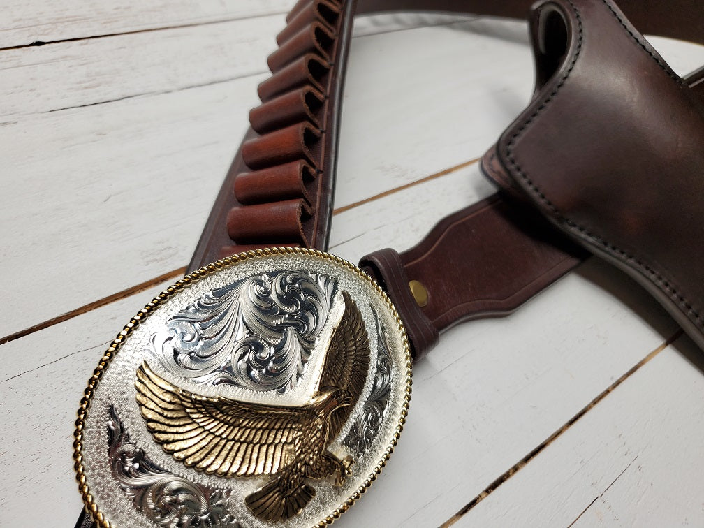 Image of the Lone Wolf Mcquade replica holster focusing on the silver and gold plated buckle, the buckle features a golden eagle and silver detailing.