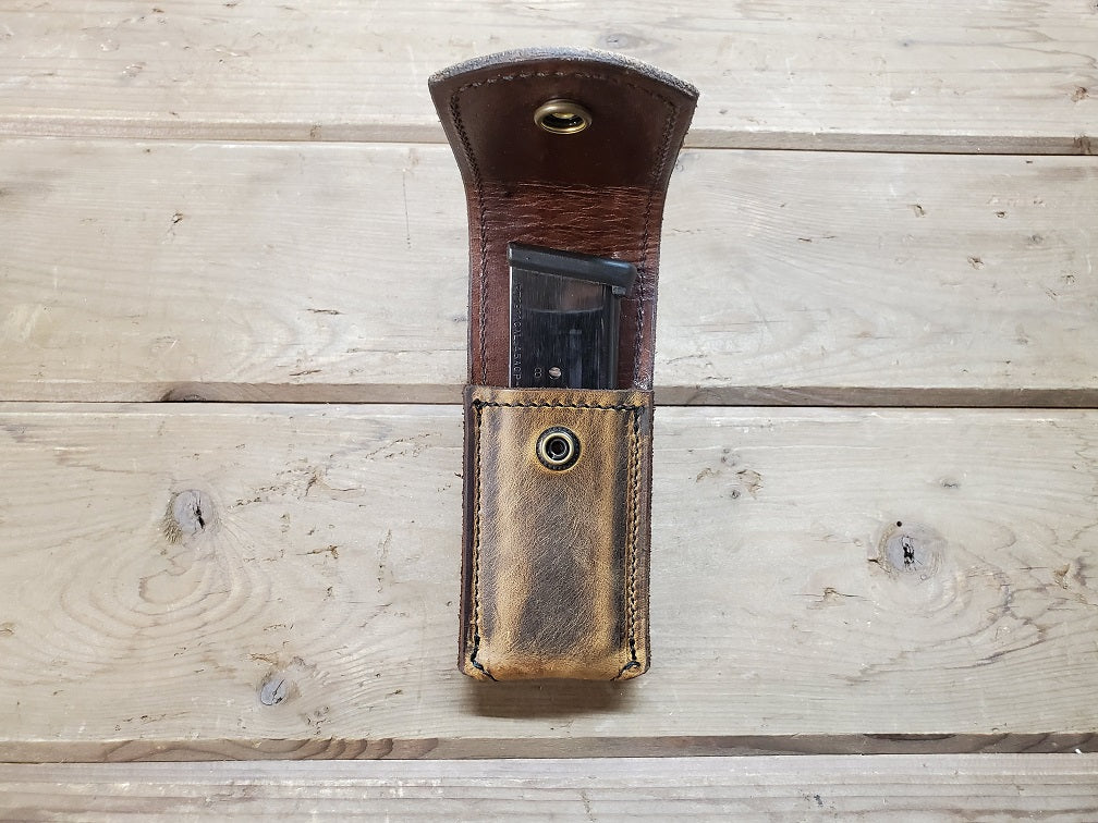 Distressed brown leather M1911 mag pouch featuring solid brass hardware with M1911 magazine inside.