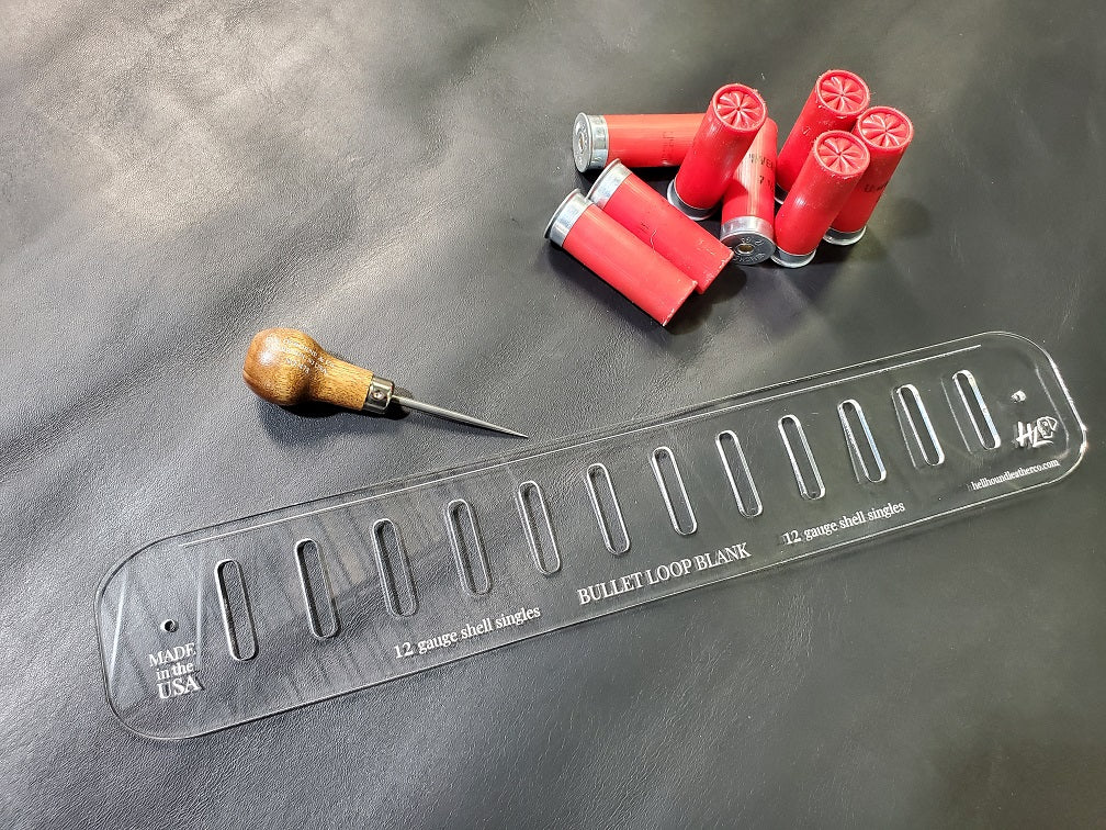 An acrylic bullet loop pattern used in leathercraft to mark the spacing between bullet loops on a western gun belt sits next to a pile of 12 gauge shotgun shells