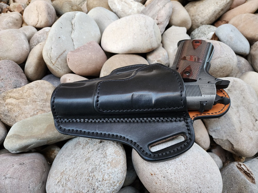 View from the top end of the black leather 1911 holster. Holstered within is a classic 1911 side arm with russet interior leather.
