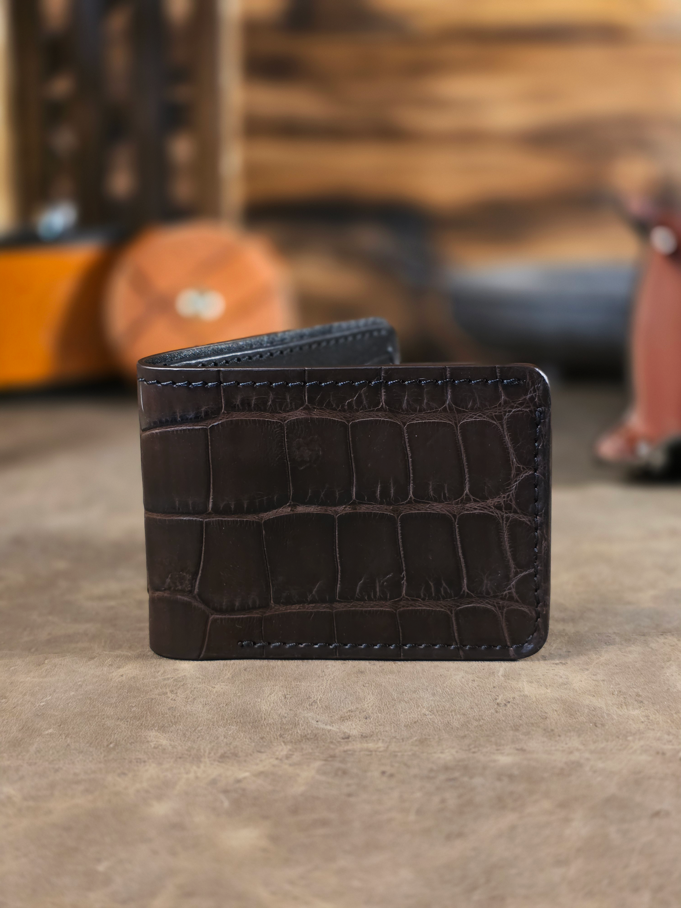 Beautiful rich brown alligator belly wallet, slightly open, showing the exotic grain of the alligator and burnished edges.