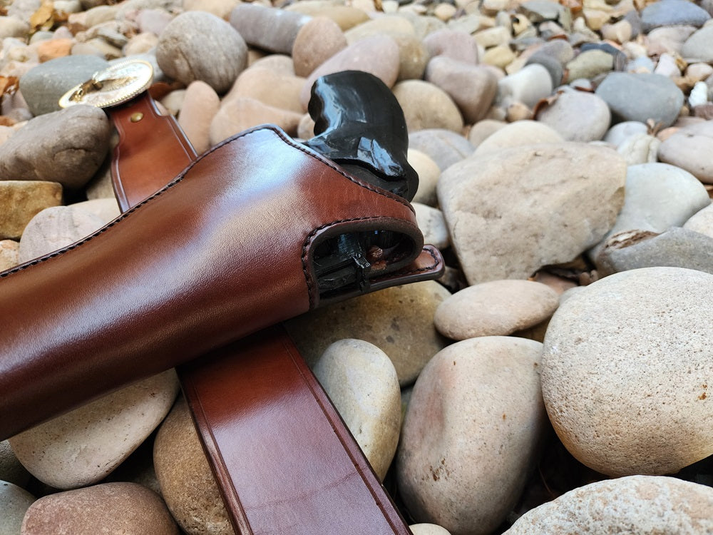 Image focusing on the holster on the Lone Wolf Mcquade gun rig, the leather brown with black stitching and solid brass hardware, the holster and belt featuring solid brass hardware.