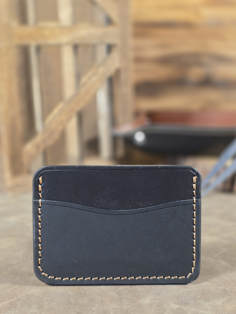 Black leather minimalist 3-pocket card wallet with a blurred background