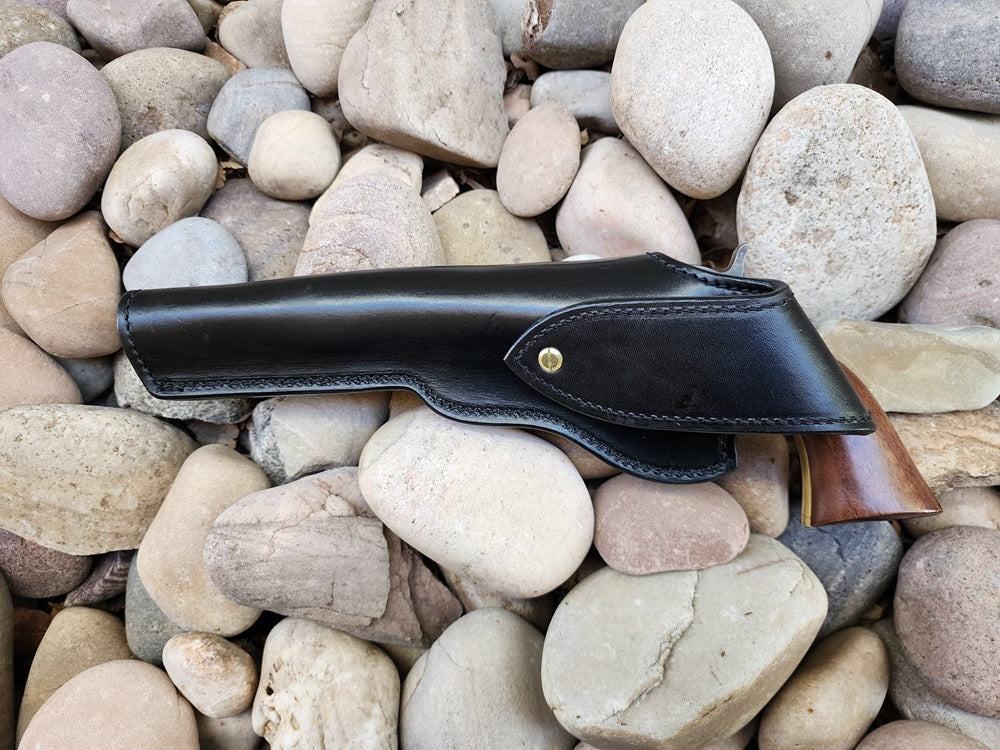 Rear view of a black leather replica of Wild Bill Hickok's holster, Holstered is a 1873 Peacemaker. The holster sits on a bed of rocks.
