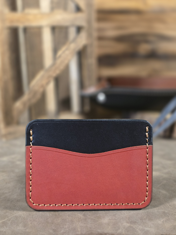 Two-tone leather wallet with red front and black back on a concrete surface.