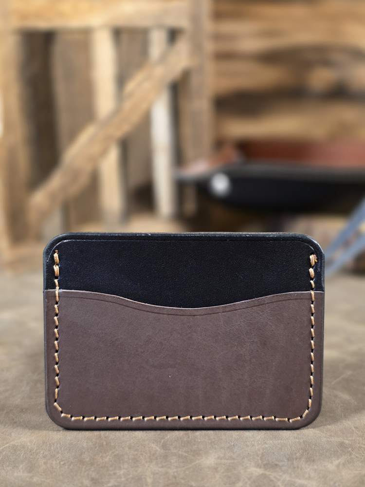 Brown leather cardholder with black interior on a wooden surface