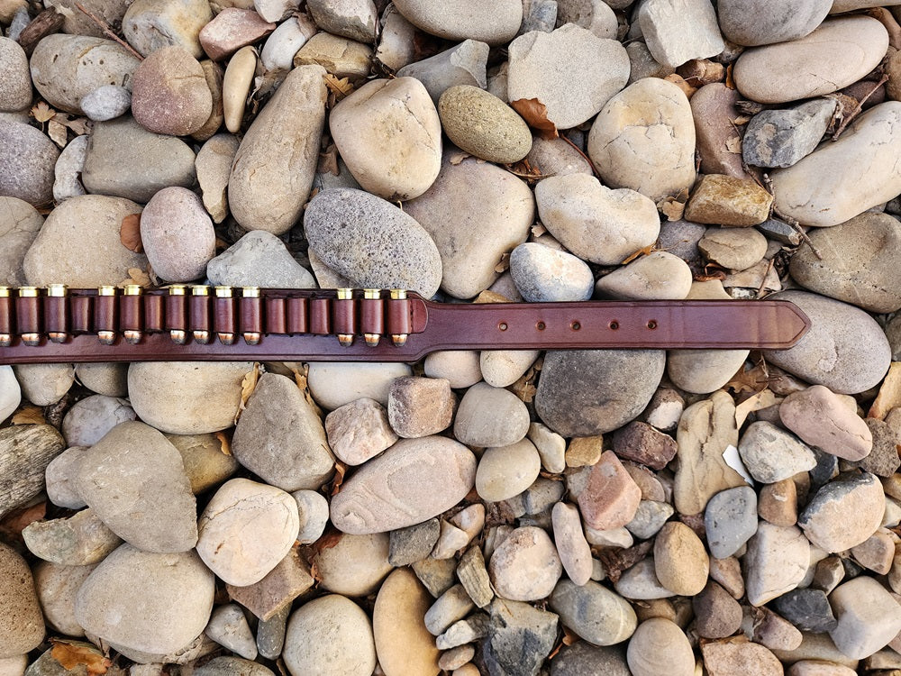 Right end of the Lone Wolf Mcquade belt, the right has the billet end of the belt and it lays on a bed of pale river rocks.