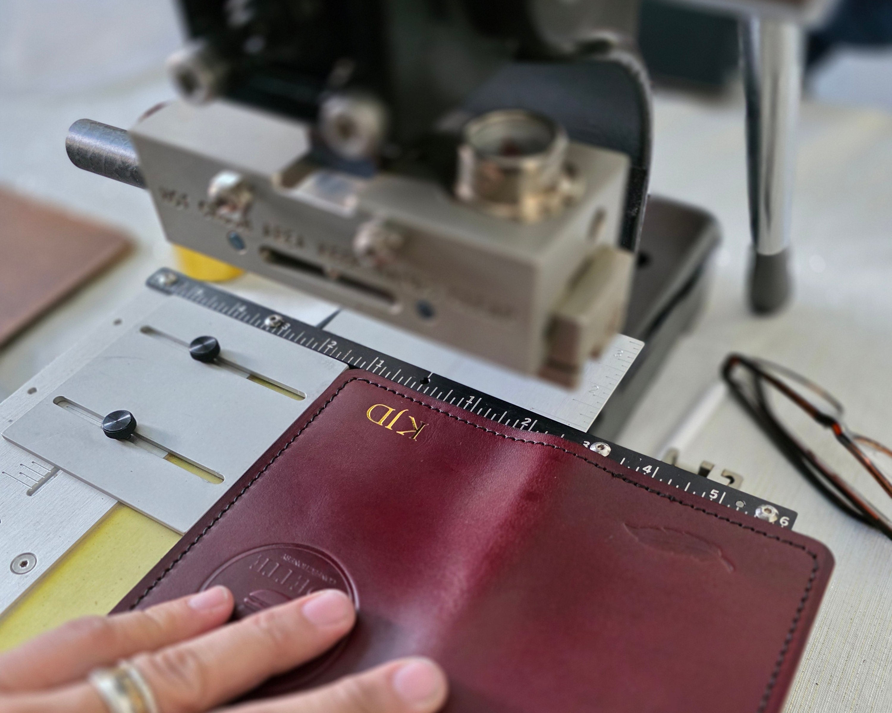 A leather journal with the initials "KJD" pressed in gold foil sits in the debossing machine at an event.