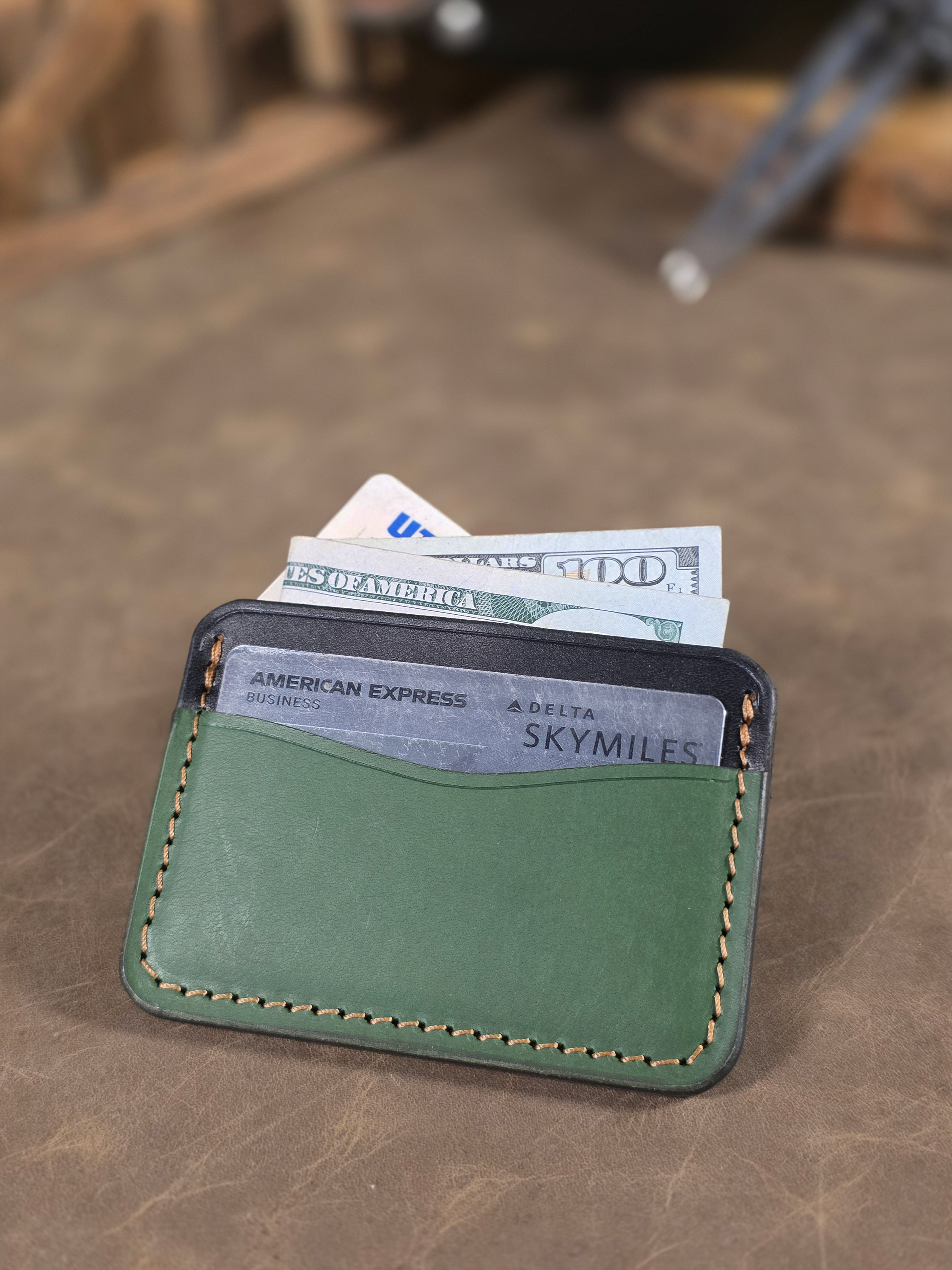 Green leather wallet with cards and money on a wooden surface