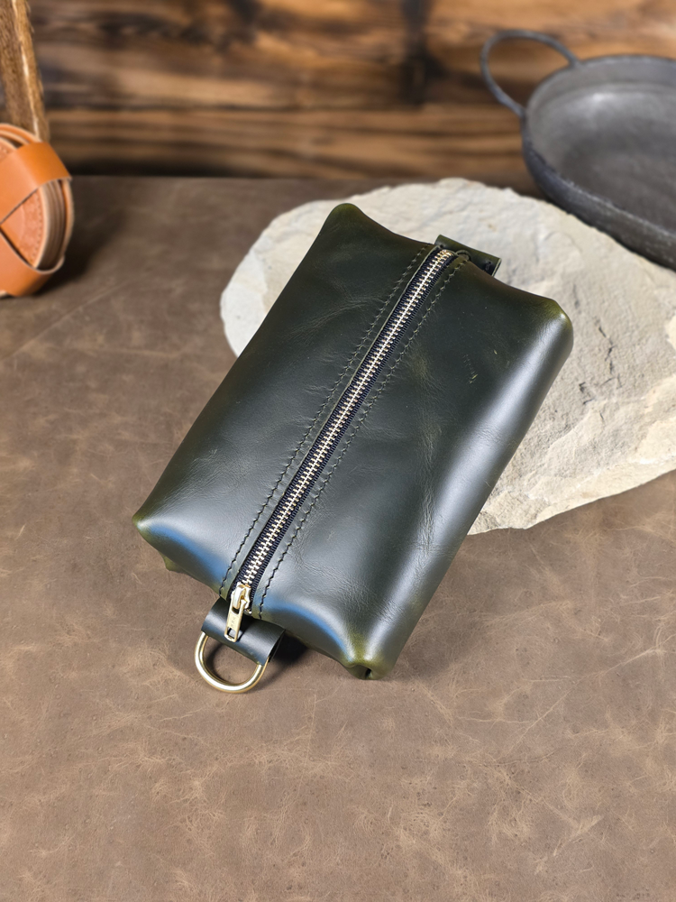 Forest Green leather pouch with a zipper on a stone surface