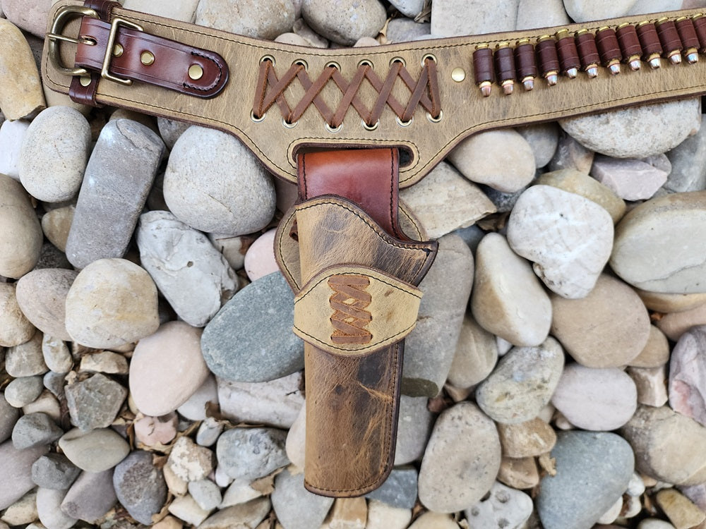 Close up shot of one of the holster on the double drop buscadero. The holster features vintage brown leather exterior and brown leather interior with a lace criss cross pattern on the collar. The entire piece is fitted with solid brass hardware.