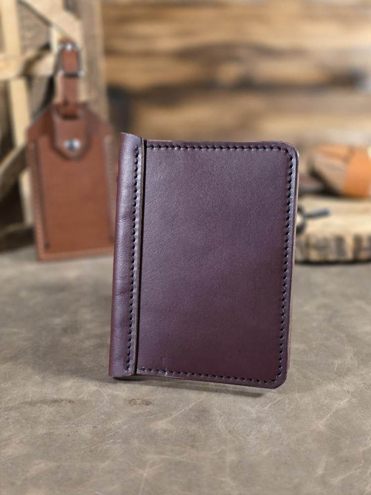 Oxblood colored leather passport travel wallet on a textured surface with blurred background