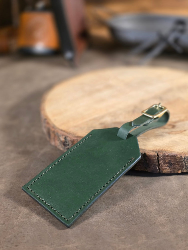 Green leather luggage tag on a wooden surface with a blurred background