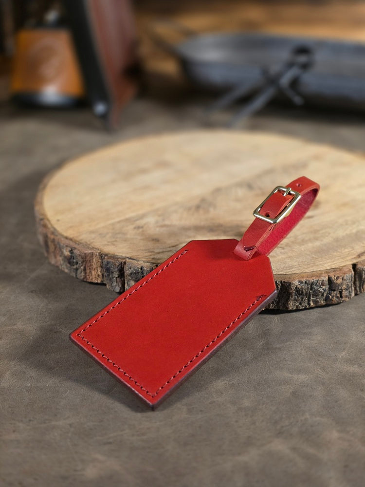 Red leather luggage tag on a wooden surface with a blurred background
