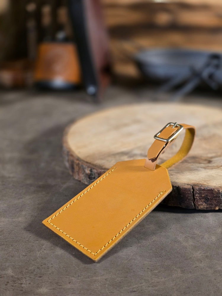 Yellow leather luggage tag on a wooden surface with a blurred background