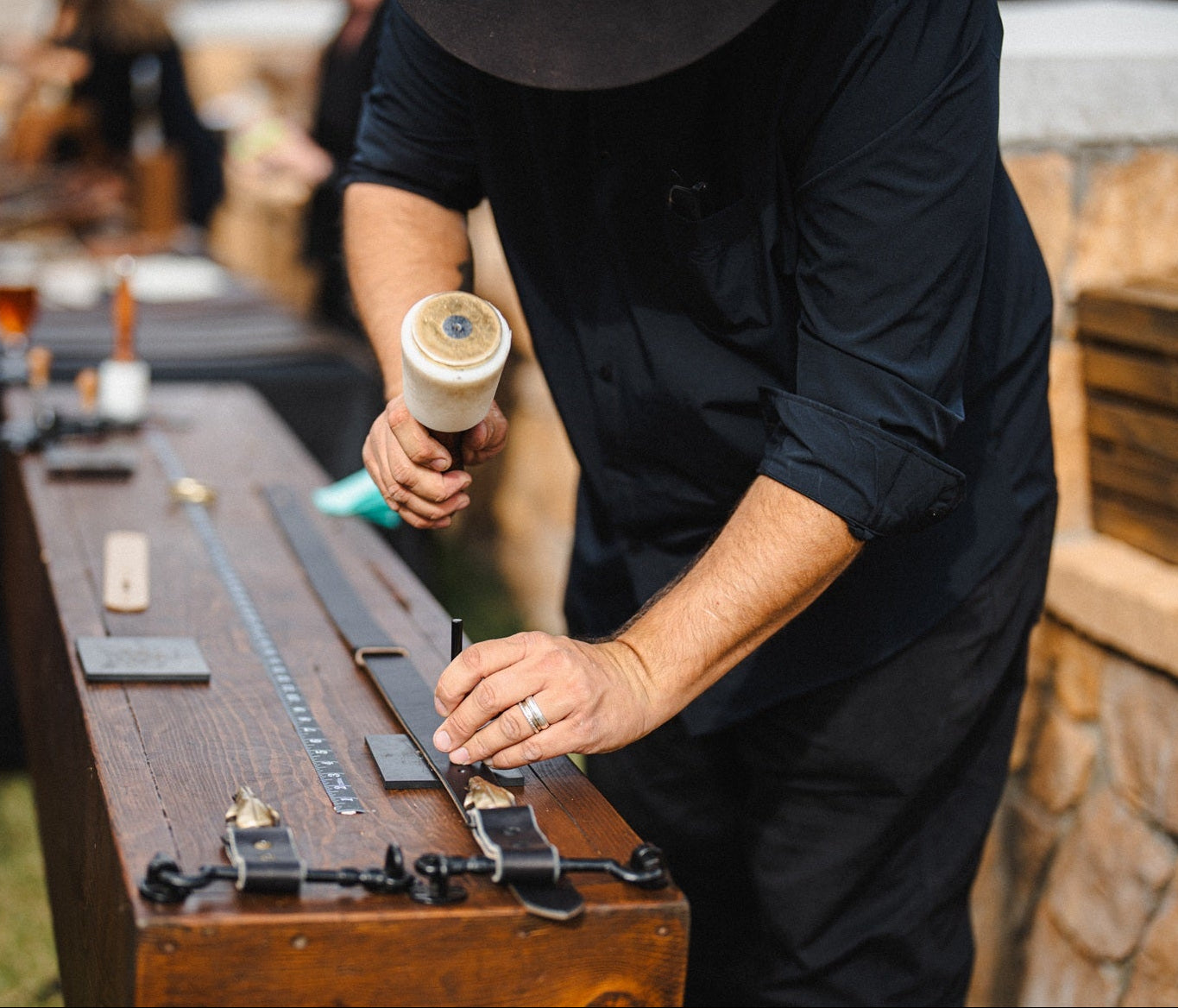 Gavin Ambrose cutting a belt to size on a mobile wooden leather workbench