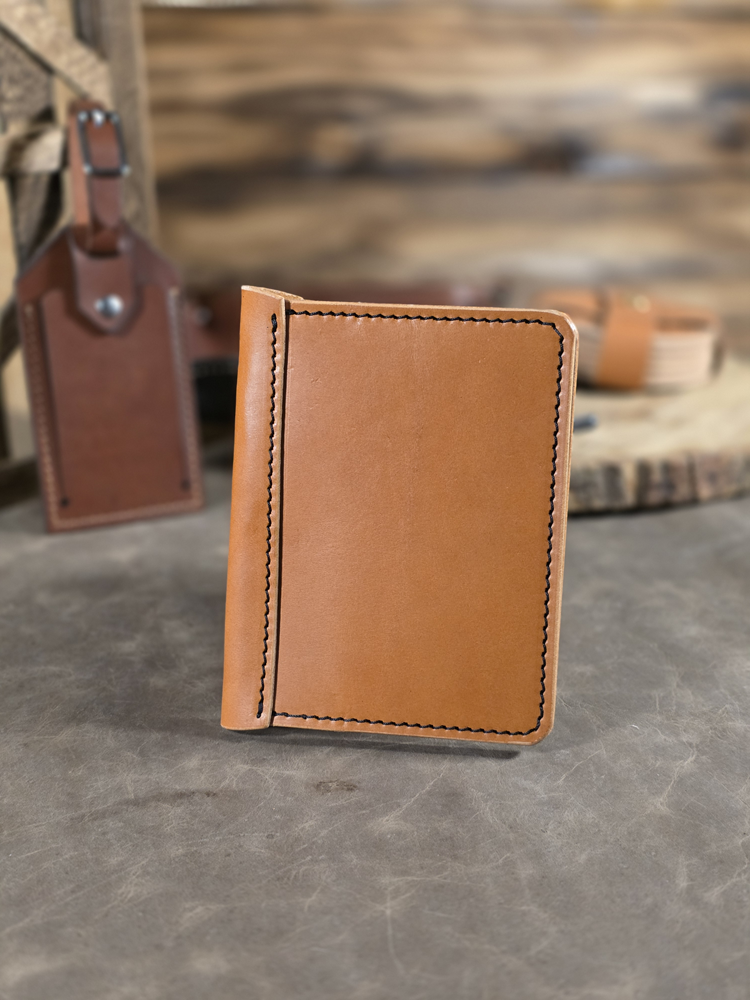 Tan leather passport travel wallet on a gray surface with blurred background.