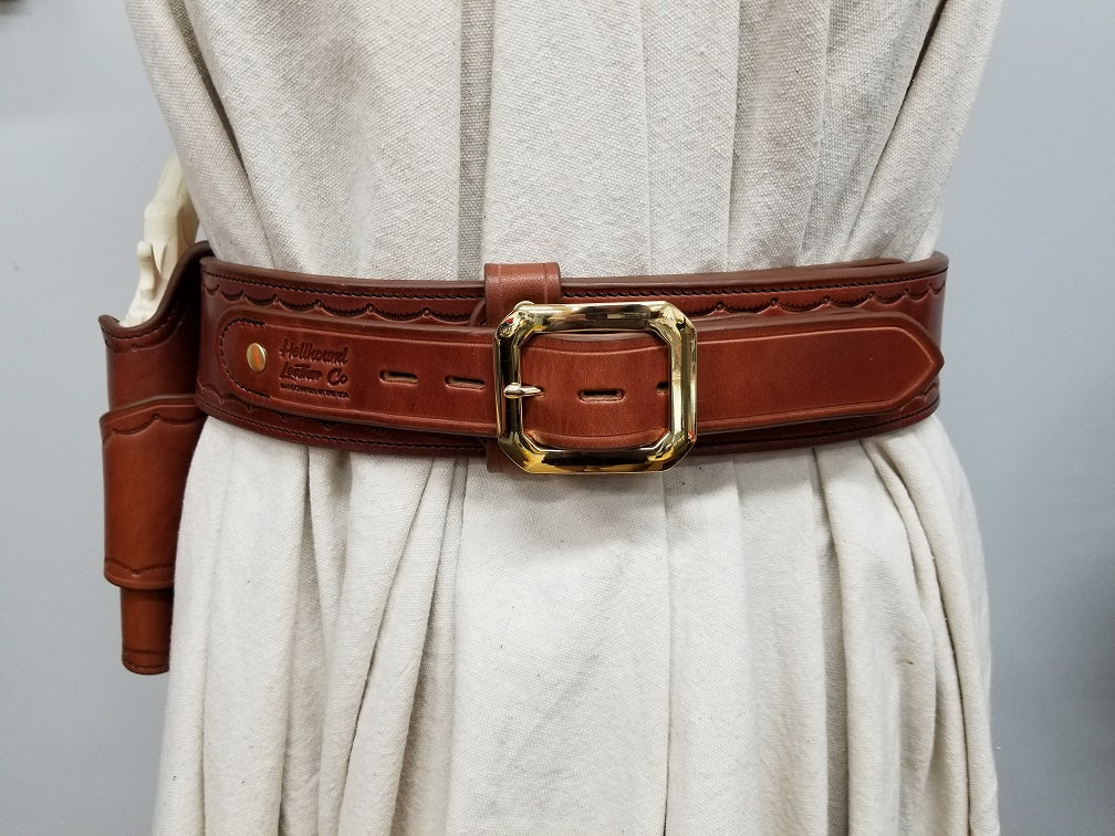 Sturdy brown leather western cowboy gunbelt with a shiny brass buckle wrapped around a mannequin draped in white canvas