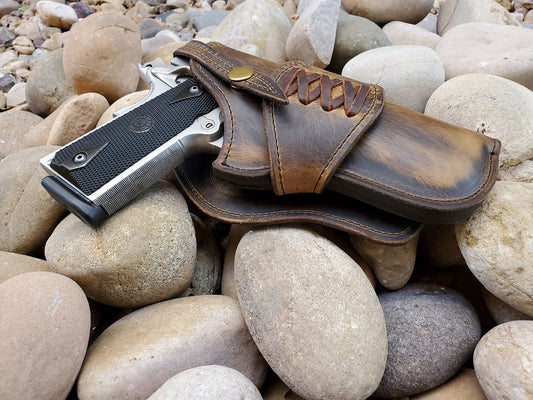 Rustic leather holster for 1911 sitting on river rocks