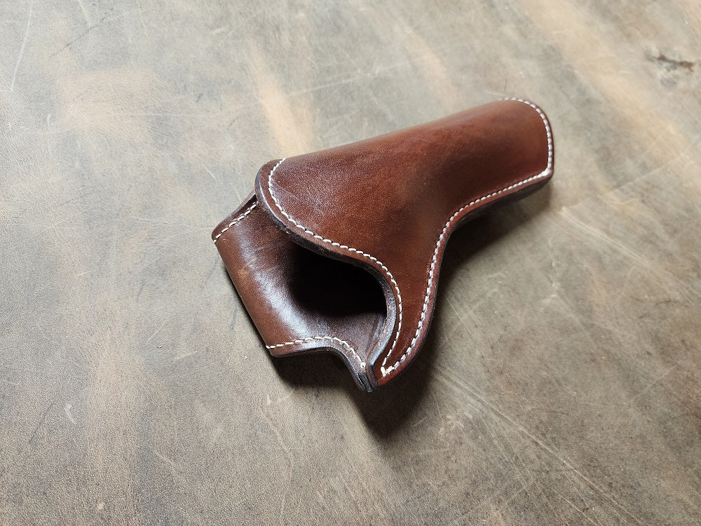 Brown leather with white stitching holster sitting with on a bed of ghostwood leather.