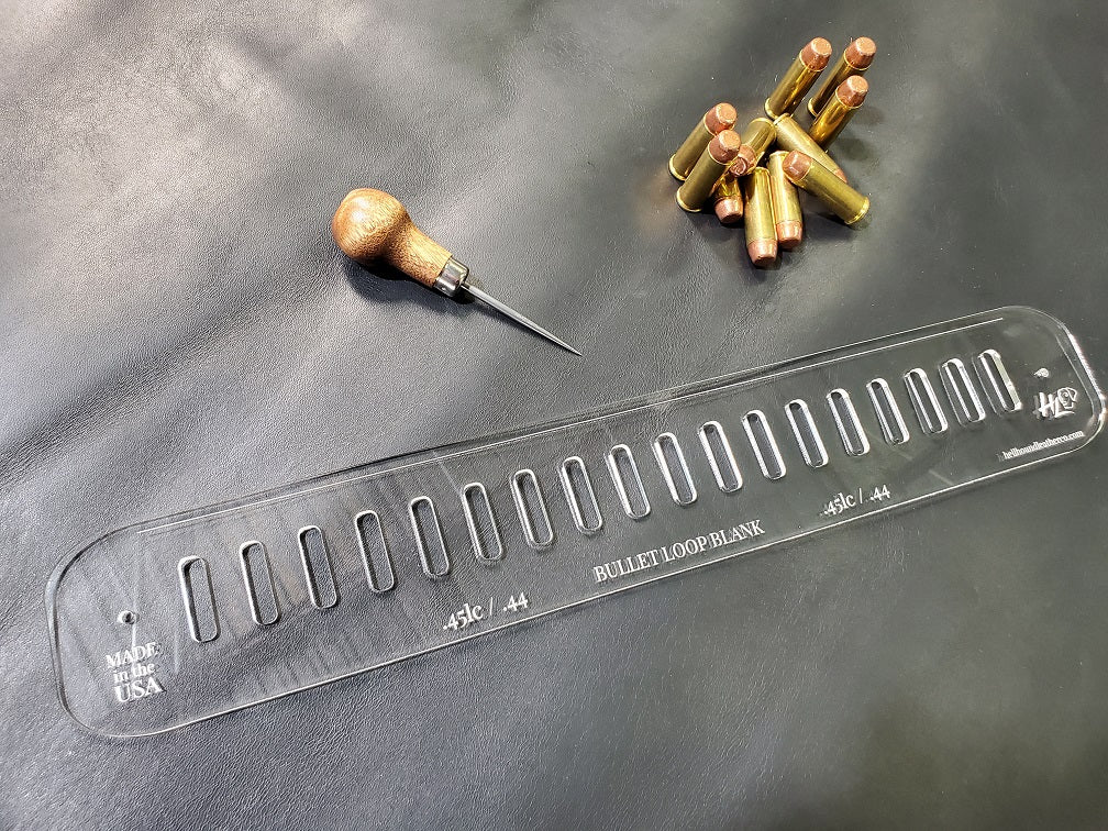 An acrylic bullet loop pattern used in leathercraft to mark the spacing between bullet loops on a western gun belt sits next to a pile of .45lc bullets.