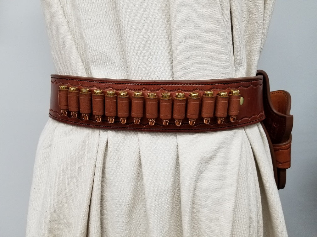 Rear view of the widow rock gun rig featuring the bullet loops on the back of the rig. The gun rig is made of brown leather and solid brass hardware with scallop pattern tooling along the borders. 