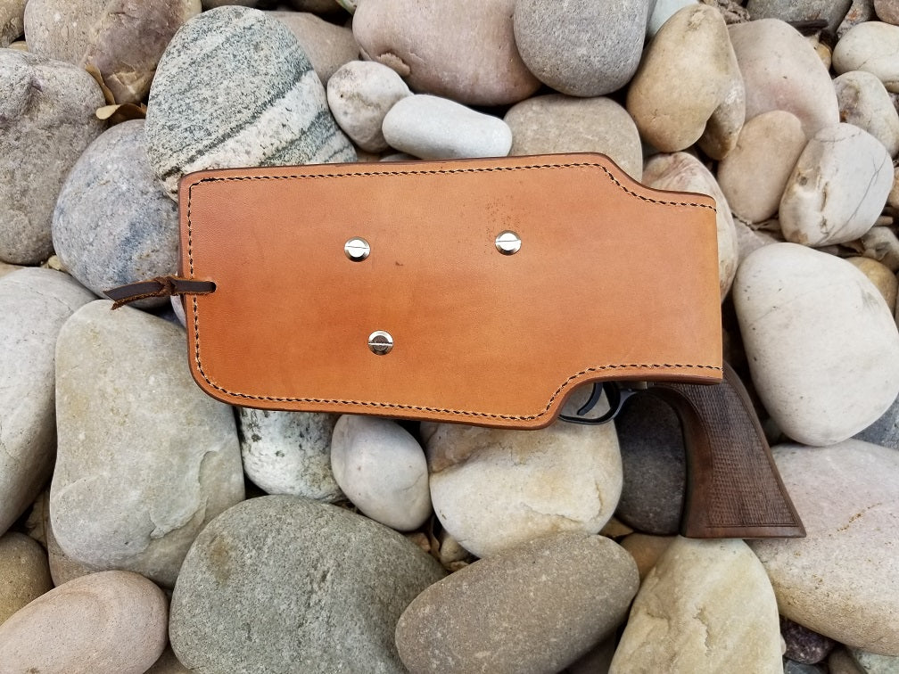 Skirt view of the widow rock holster, the leather is russet and has nickel hardware. The holster sits in a bed of rocks.