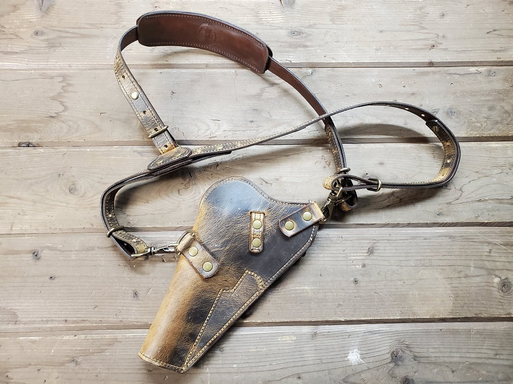 Rear view of distressed brown holster featuring solid brass hardware displayed on wooden slats.