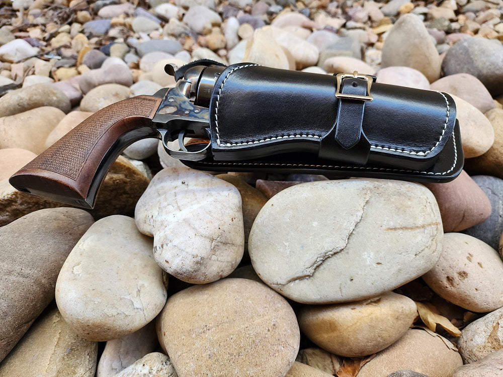 Bottom end of a black leather holster showcasing the white stitching and solid brass hardware.